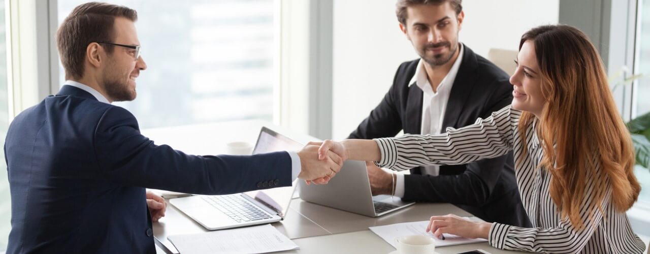 Business people shaking hands after a deal for innovation funding.