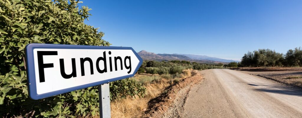 Barron land with a sign "labelled funding" pointing down a road. The road most likely leads to venture debt funding.