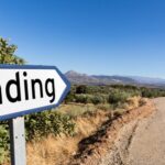 Barron land with a sign "labelled funding" pointing down a road. The road most likely leads to venture debt funding.
